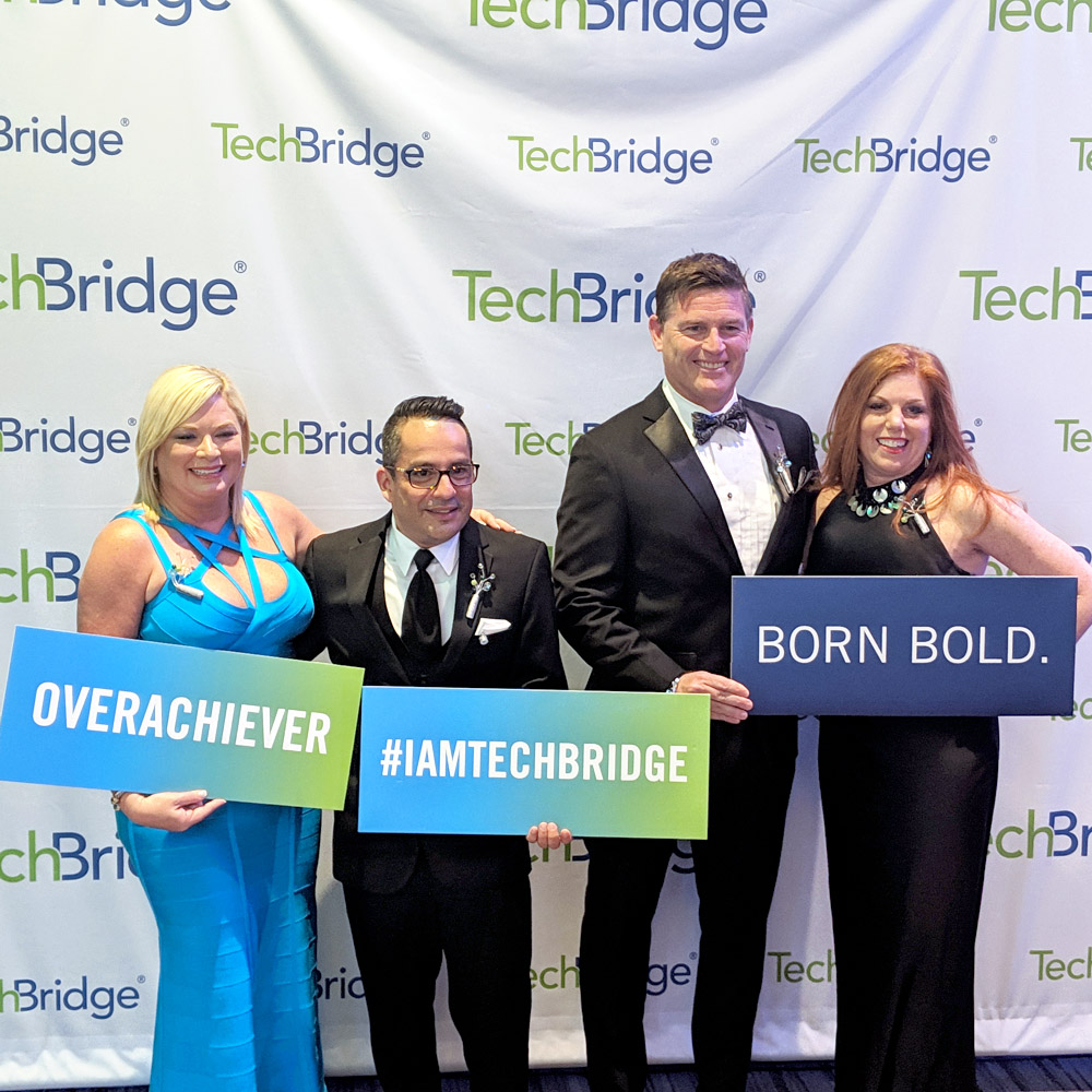 Digital Ball participants posing with signs that say “OVERACHIEVER,” “#IAMTECHBRIDGE,” & “BORN BOLD.”