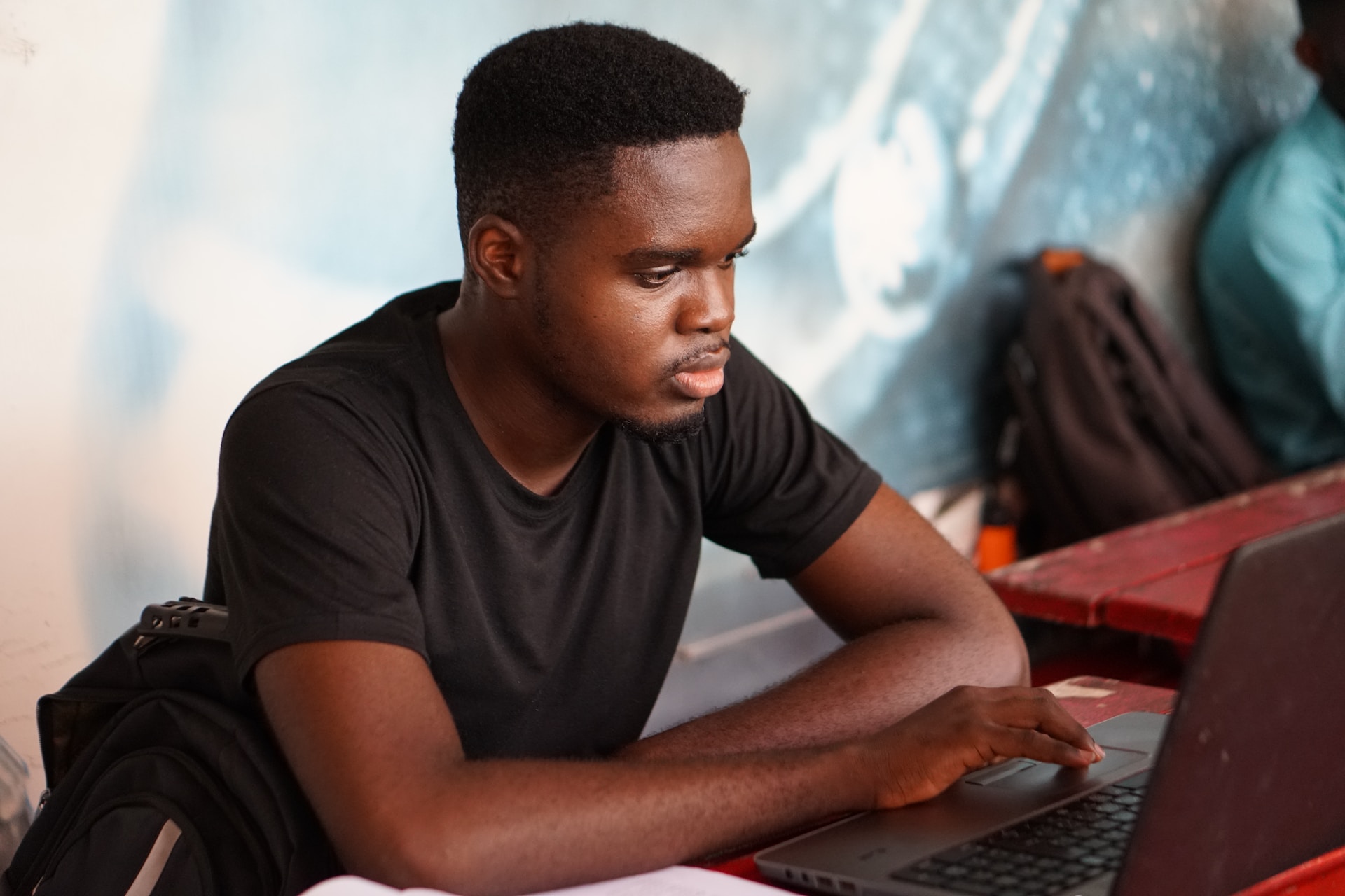A young Black student working at a laptop.