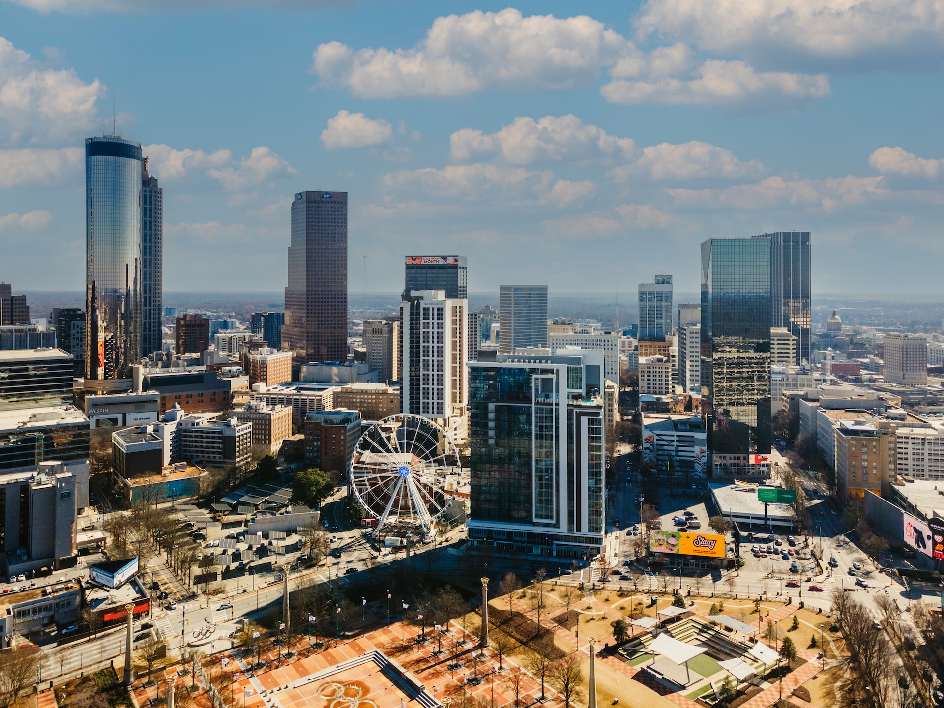 Aerial view of downtown Atlanta skyline during the daytime. The ferris wheel and several tall, glass skyscrapers are pictured.