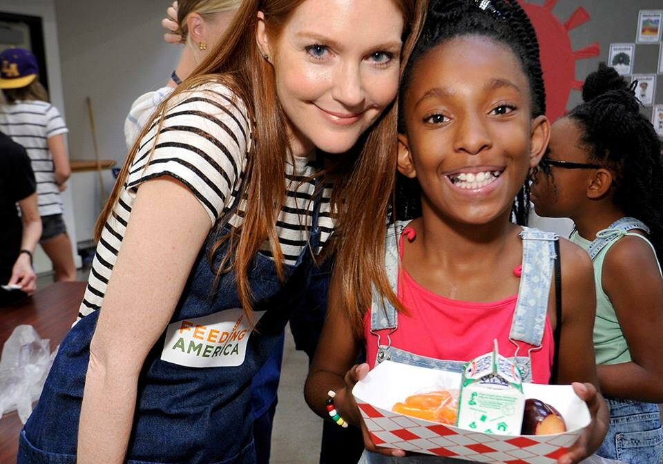 Photograph of smiling children receiving food at Feeding America event.