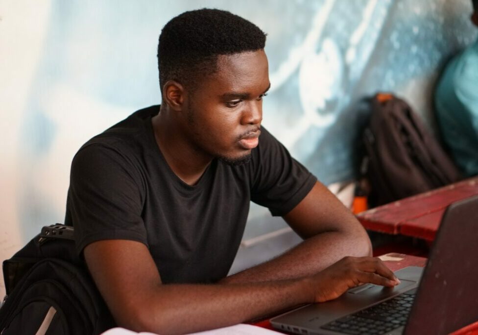 A young Black student working at a laptop.