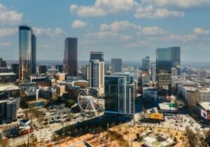 Aerial view of downtown Atlanta skyline during the daytime. The ferris wheel and several tall, glass skyscrapers are pictured.